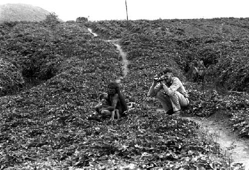 Karl Heider negatives, New Guinea; Robert Gardner taking a shot of a woman and a child