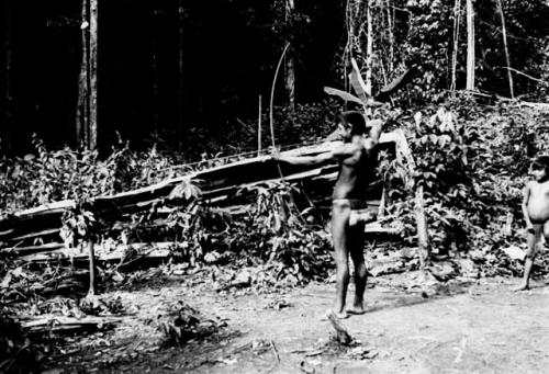 Man with bent bow showing method of using bow and arrow