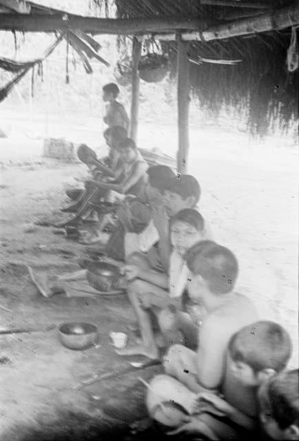 Men drinking cassiri -- sitting on one of long log benches frequently found in Carib houses