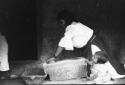 Woman grinding corn with stone mortar and pestle