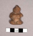 Small seated yellow pottery figurine