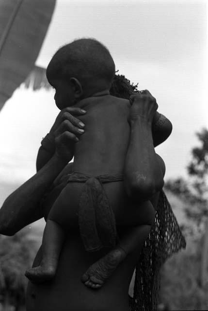 Girl holds Wamasue, who wears bark cloth 'diaper' (tani)