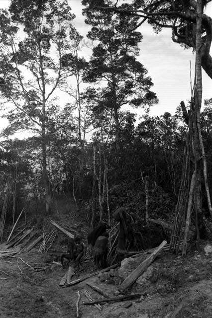 Musanima. Groundplanks laid down for pig sties. Men and women at fire.