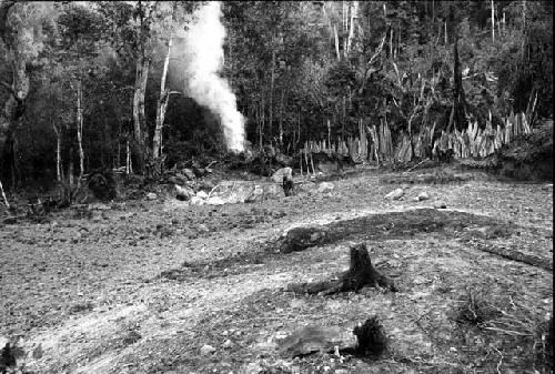 Musamina. area cleared for village; lumber stacked against rocks bg.