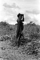 Dumakonem. woman straightens after dropping thatch burden.