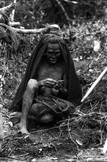 old woman folds cigarette.