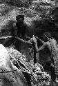 Ilueaima ('Kurelu Salt Well'). woman hands banana trunk to man.