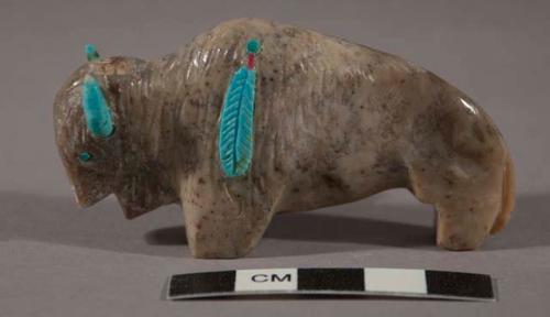 Fetish buffalo of gray and tan stone with turquoise horns, eyes and inlaid feather on left shoulder