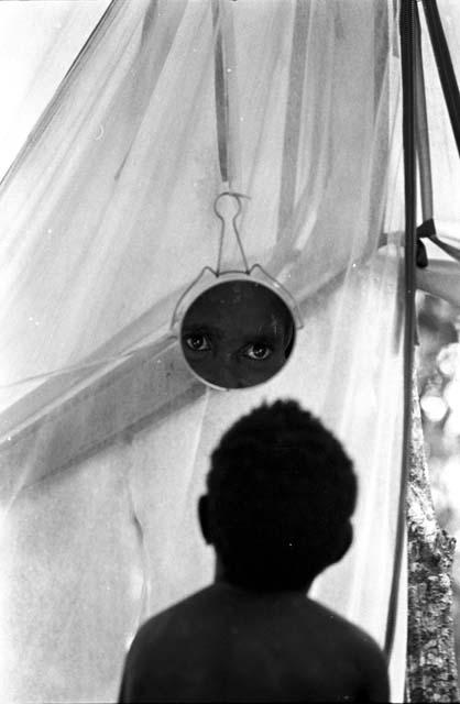 Karl Heider negatives, New Guinea; Child looks in mirror