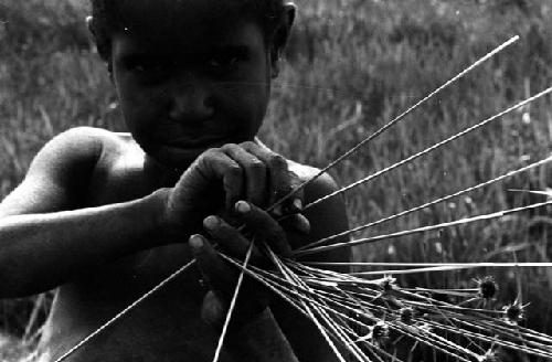 Karl Heider negatives, New Guinea; Milika's son making grass stem toys