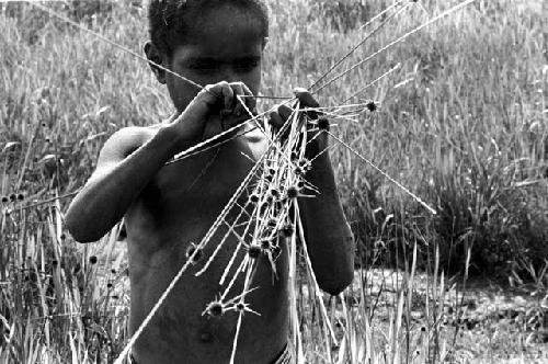 Karl Heider negatives, New Guinea; Milika's son making grass stem toys