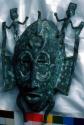 Kepele mask with figures on each side of crown,  copper with green patina.  11 1