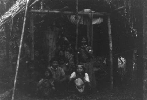 Men, women and children in typical costume and typical temporary hut