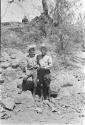 Unidentified men standing among rocks and brush