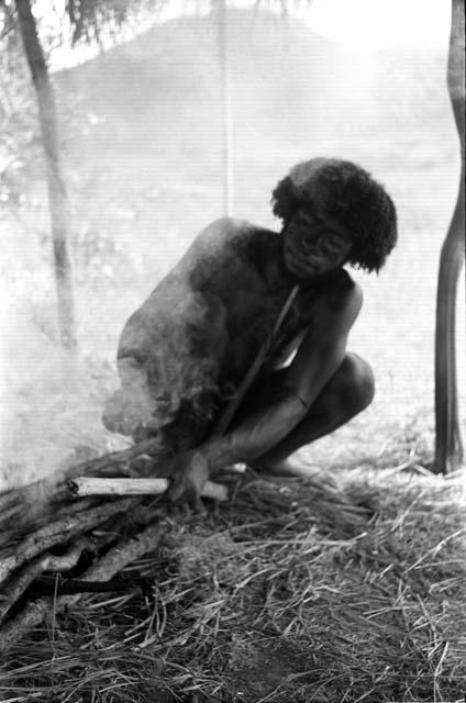 Asukuwan tending a fire