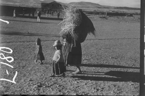 Woman carrying hay with small children