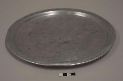 Flat lid for aluminum cooking pot; ninth of set of 12; impressed mark of globe with scales, draped with banner reading E. I. TACHABROS. TM REGD, crown above, PURE ALUMINUM beneath