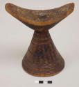 Wooden headrest with inverted conical base; carved design in horizontal bands, painted red and black
