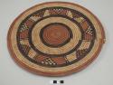 Coiled basketry plate; brown center, black and brown radiating design, brown rim