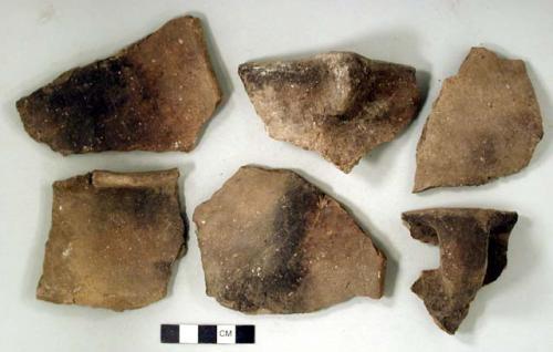 Ceramic, earthenware rim, body, and handle sherds. Undecorated and some charred. Shell temper. One lug.Two rim sherds cross mend. One rim sherd and one body sherd crossmend.