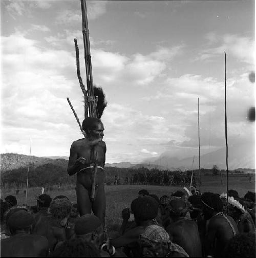 Polik standing amongst seated men