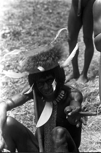 Adorned man gesturing towards camera; near Wali's kaio