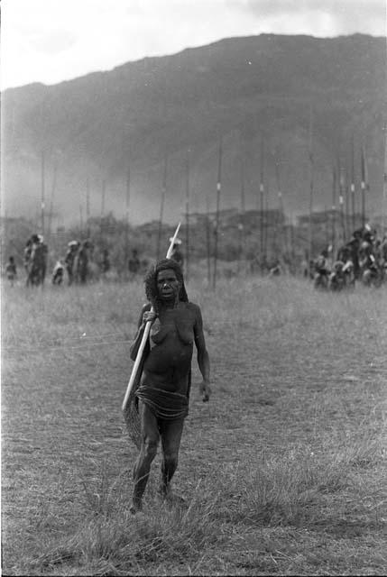 Woman standing on the field, with warriors behind her, at an Etai