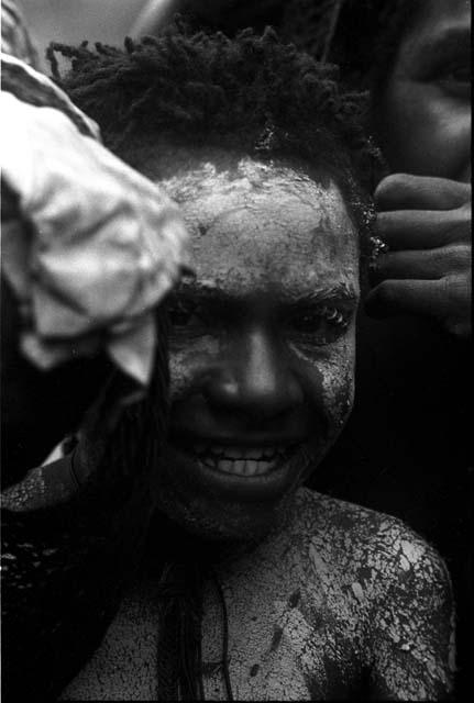 Woman with chalked face looks towards the camera