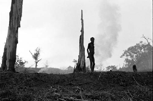 An elderly man stands in his garden