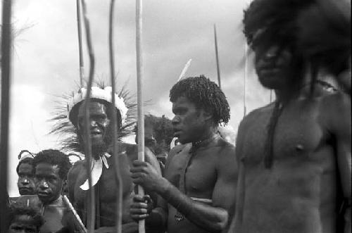 Men standing and singing at an Etai; spears in hand