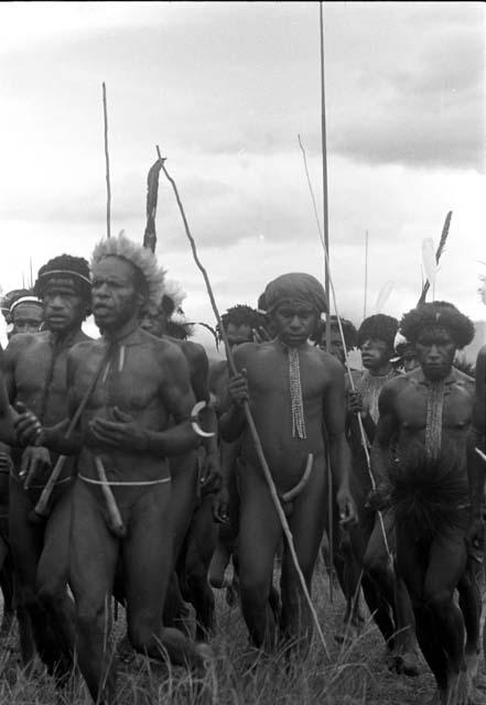 Close shot of men dancing at an Etai, spears in hand