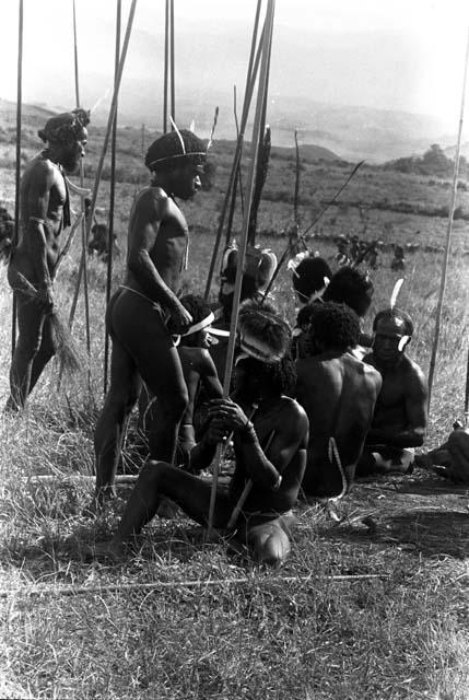 Men seated, their spears around them