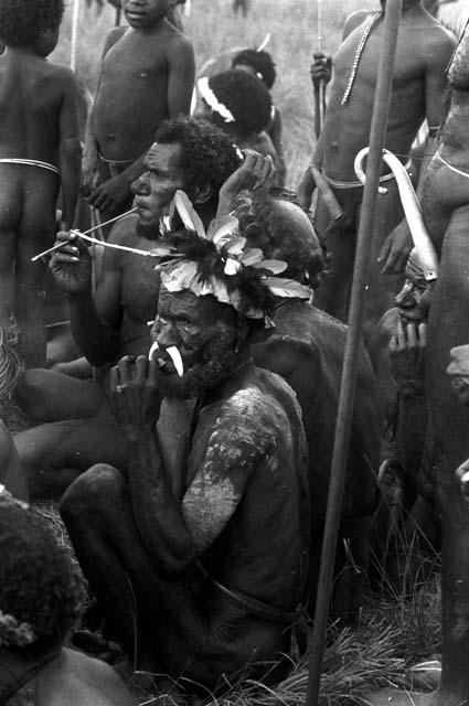 Older men seated at an Etai, boys standing around them