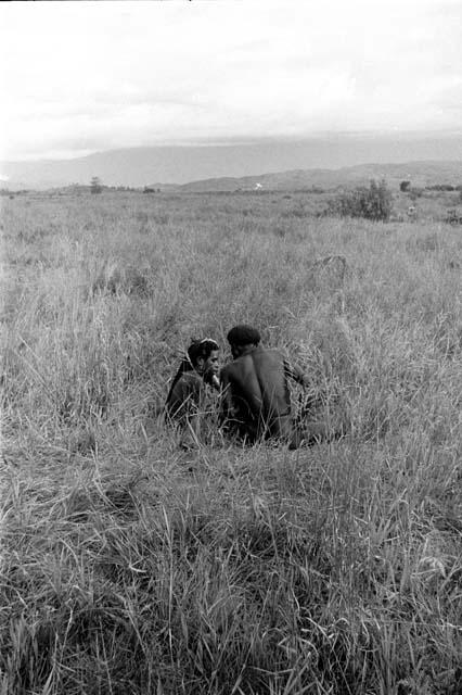 Men talk while seated in the grass