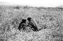 Men talk while seated in the grass