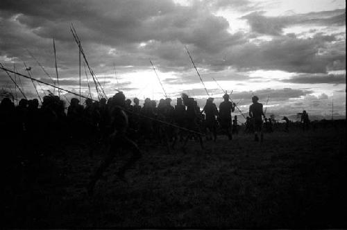 Dancing group of men silhouetted against the low sun