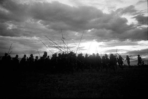 Dancing group of men silhouetted against the low sun