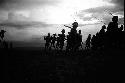 Dancing group of men silhouetted against the low sun; video camera on left of frame