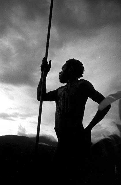 Silhouetted man leaning on his spear