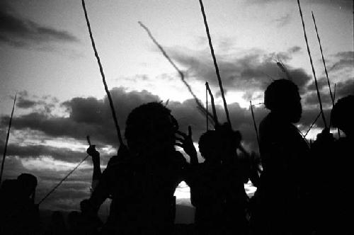 Silhouetted figures and spears; dancing