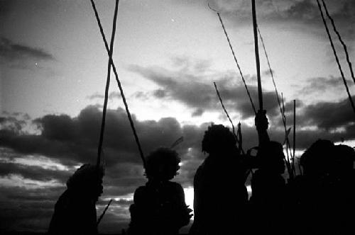 Silhouetted figures with their spears, dancing