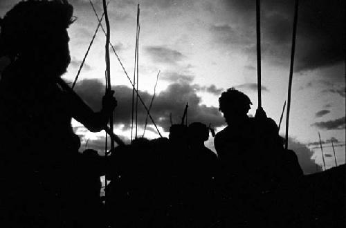 Silhouetted figures with their spears, dancing