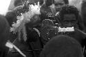 Man with feather headdress looks through Filmo video camera