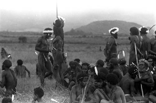 Men's group seated at an Etai, Polik standing in the center