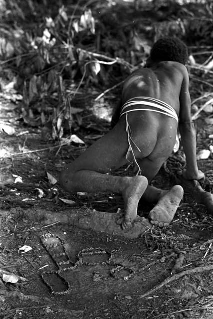 Child making miniature sili on the dirt with sien seeds