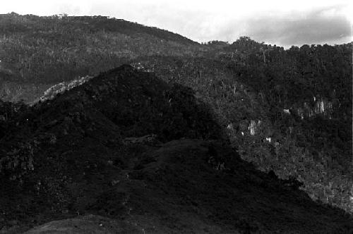 Distant view of a sili in the shadow of a hill, at the entrance to the salt well trail; view of surrounding hills