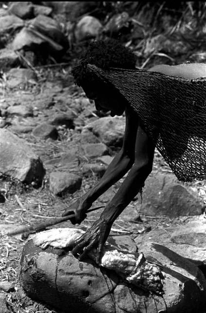 A woman prepares a haki stalk to dip into the brine of the salt well