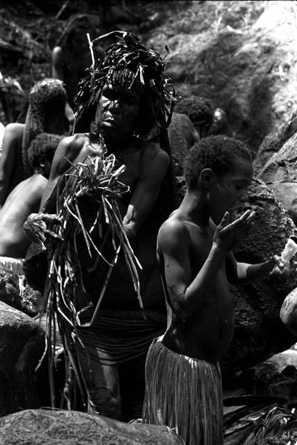 Child eating as the women behind her work at the salt well