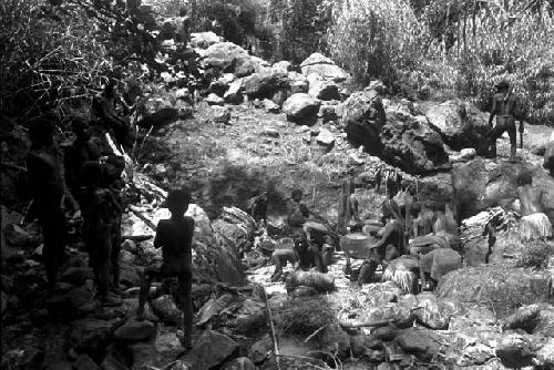 Men on rocks surrounding the salt well watch the women as they work