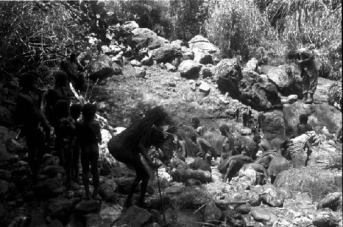 Men on rocks surrounding the salt well watch the women as they work